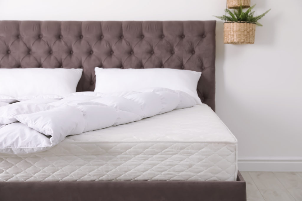 Comfortable bed with new mattress in room. Healthy sleep