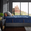 Side view of the Stearns and Foster Marcela ultra plush mattress styled with pillows on a dark gray upholstered tufted bed frame.
