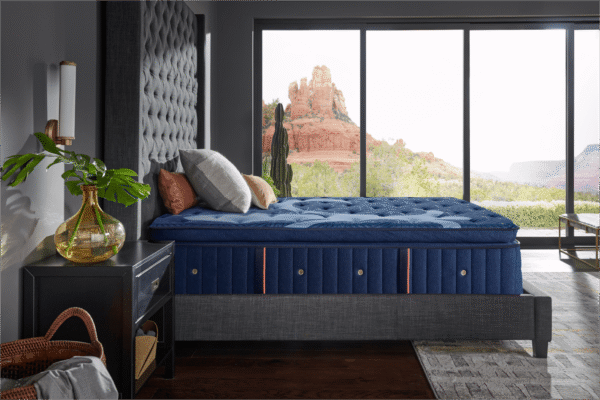 Side view of the Stearns and Foster Marcela ultra plush mattress styled with pillows on a dark gray upholstered tufted bed frame.